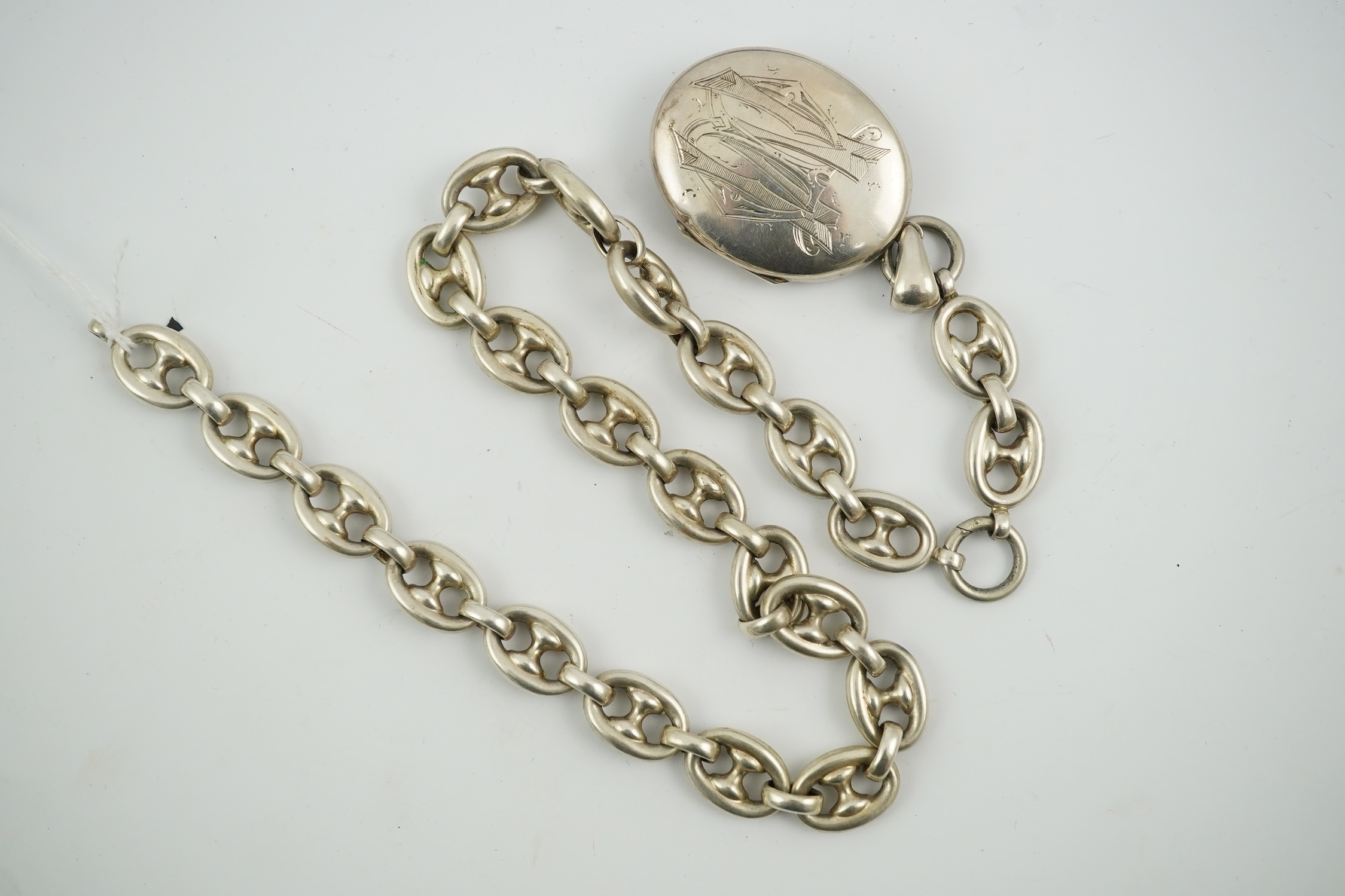 A late Victorian white metal oval locket with Japonaiserie decoration, 47mm, on a white metal chain. Condition - fair to good